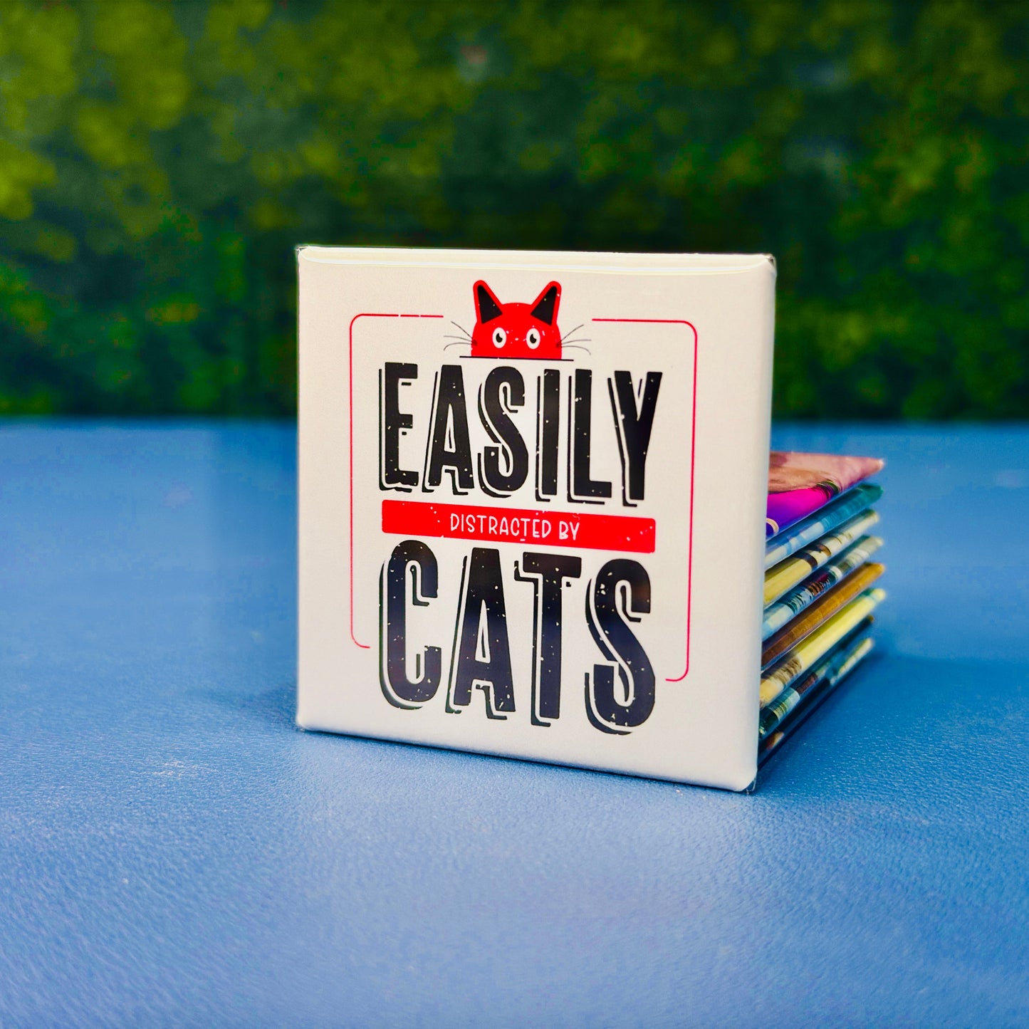 Funny square cat magnet featuring bold vintage-style lettering with the phrase “Easily Distracted by Cats” and a red cartoon cat peeking over the top. A playful and relatable gift for cat lovers, pet parents, and anyone who proudly prioritizes feline distractions. Perfect for fridges, lockers, cubicles, or home office spaces. Great for gifting or daily cat-themed decor.