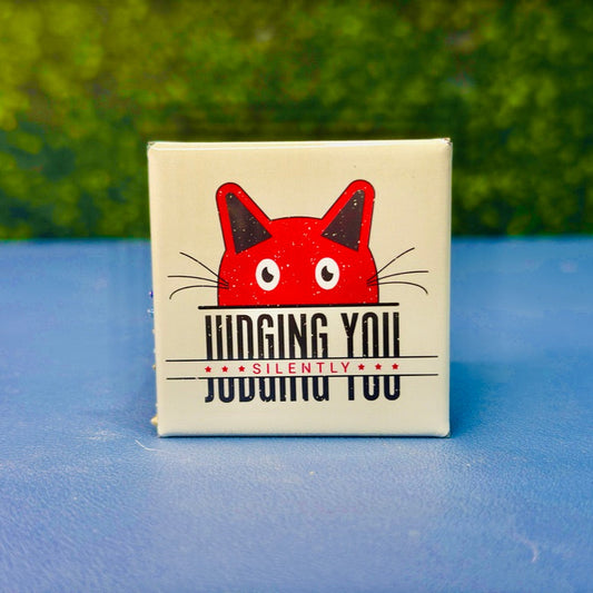 Square magnet featuring a bold red cartoon cat peeking above the sarcastic phrase “Judging You Silently” in distressed black and red lettering. Perfect for cat lovers with attitude, sassy pet parents, or anyone who appreciates dark humor. A hilarious cat-themed gift for birthdays, stocking stuffers, or fridge flair. Great for office desks, lockers, or snarky home decor.