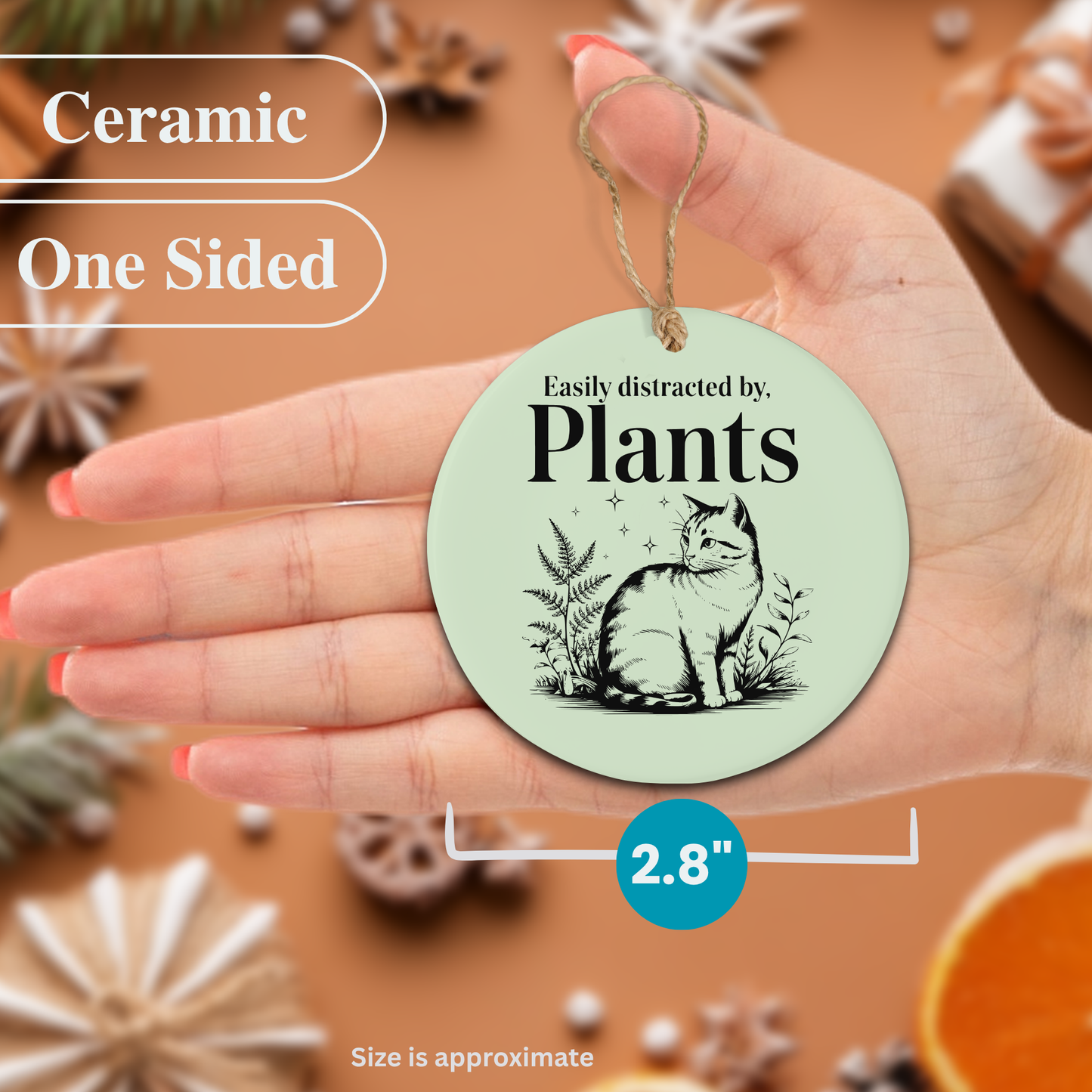 Round ceramic ornament with a cat design and text 'Easily distracted by plants' held in a hand.