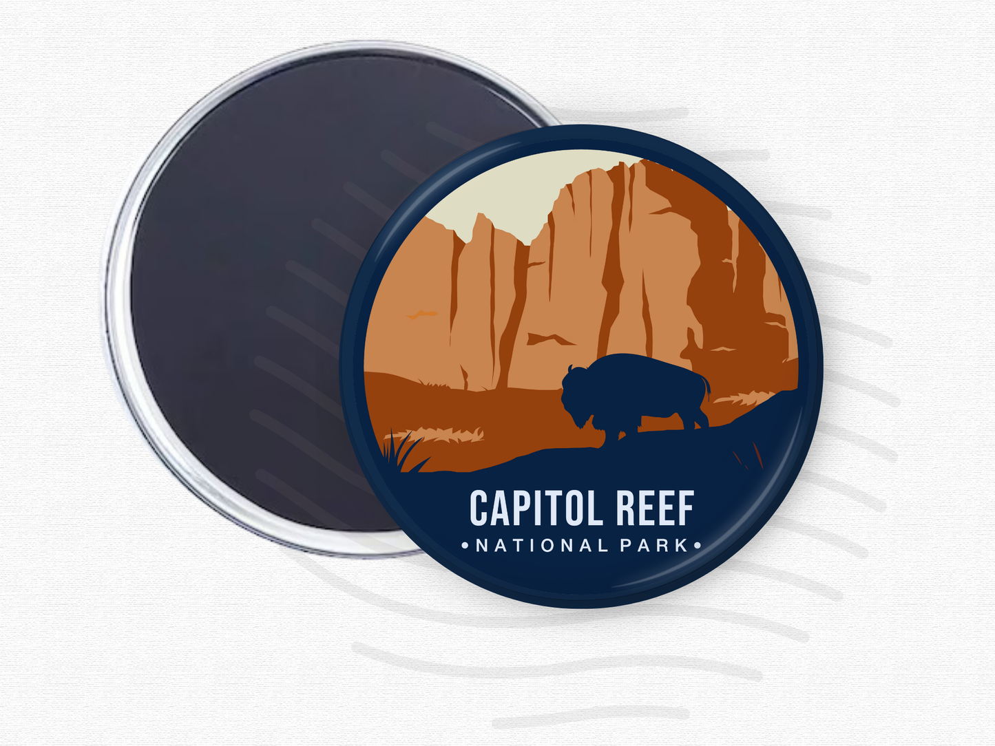 Round magnet featuring Capitol Reef National Park with towering rust-colored cliffs and a dark silhouette of a bison in the foreground.