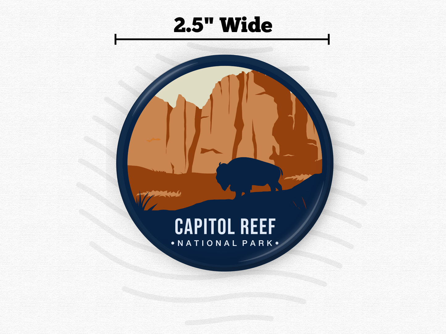Round magnet featuring Capitol Reef National Park with towering rust-colored cliffs and a dark silhouette of a bison in the foreground.