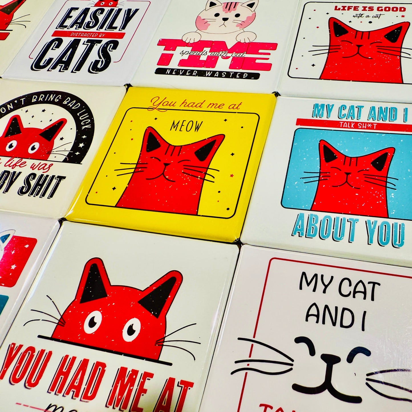 Collection of cat-themed magnets with various designs and text.