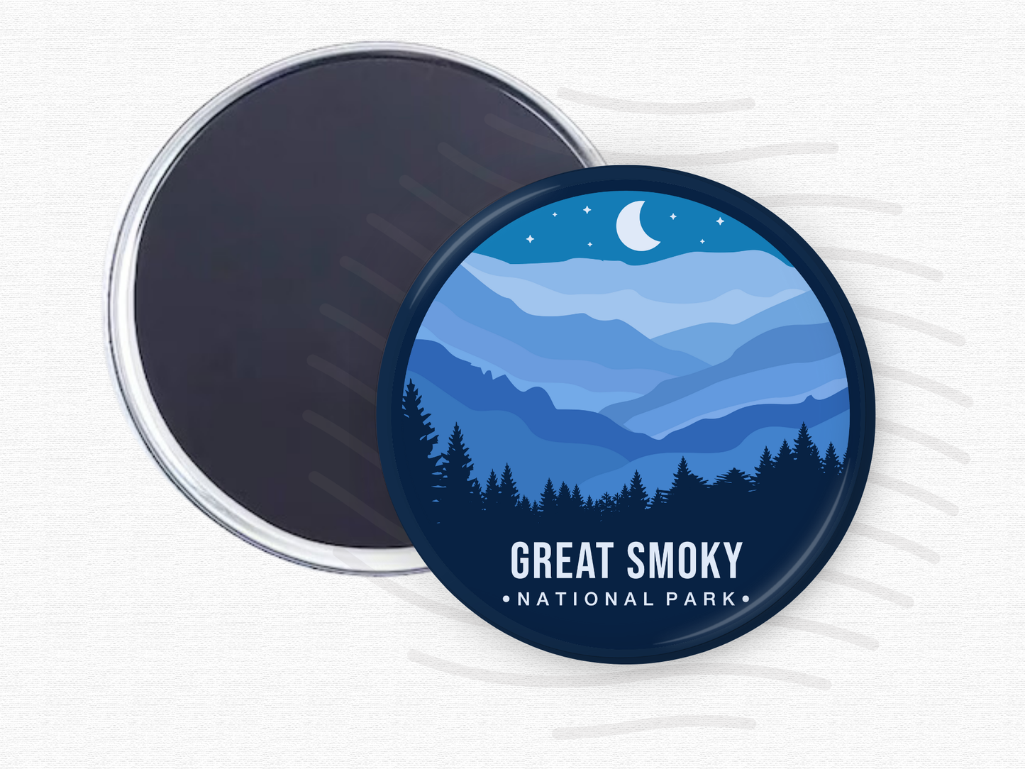 Round magnet of Great Smoky Mountains National Park featuring layered blue mountain ridges under a crescent moon and starry night sky with a silhouette of pine trees in the foreground.