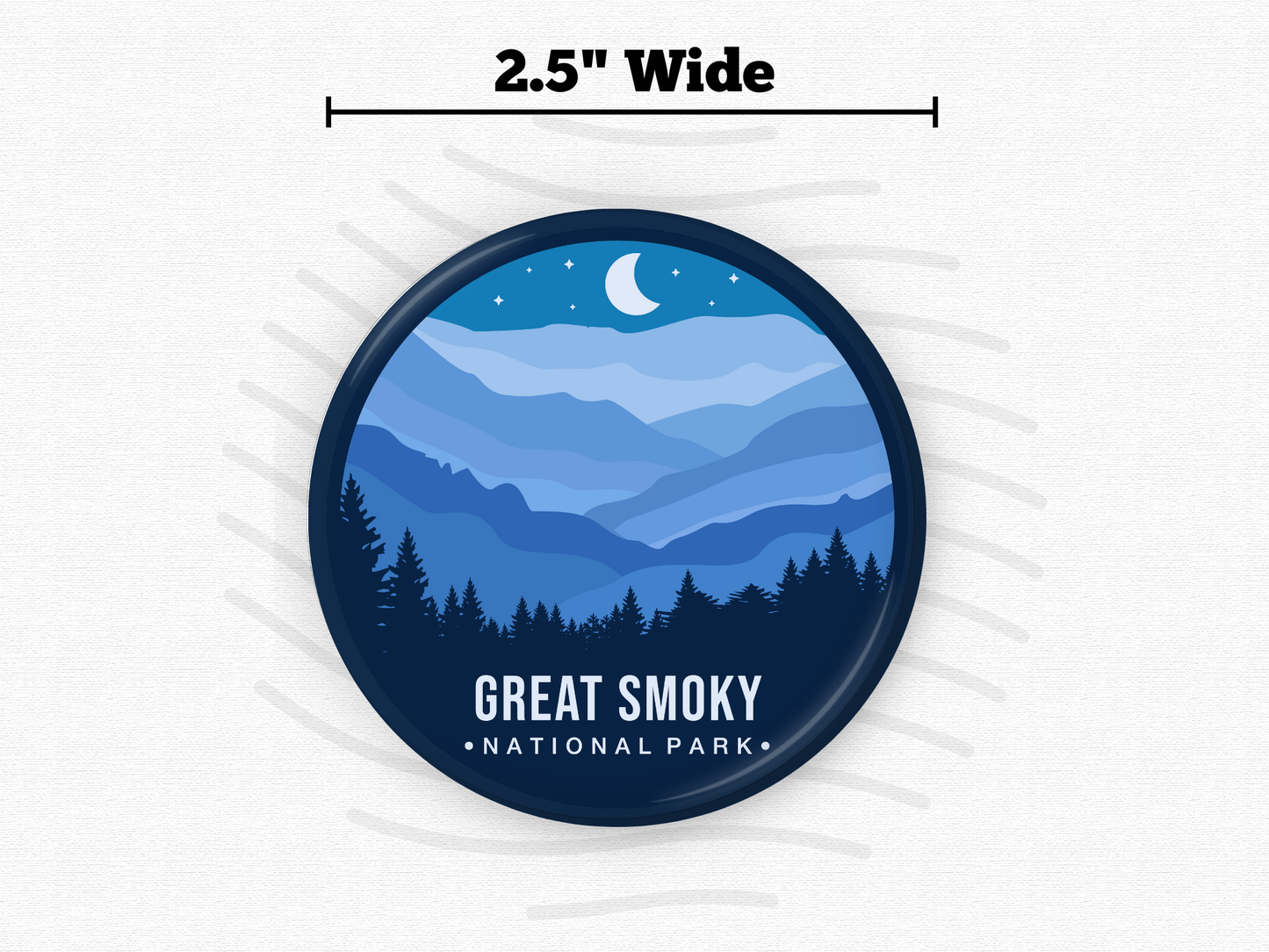 Round magnet of Great Smoky Mountains National Park featuring layered blue mountain ridges under a crescent moon and starry night sky with a silhouette of pine trees in the foreground.