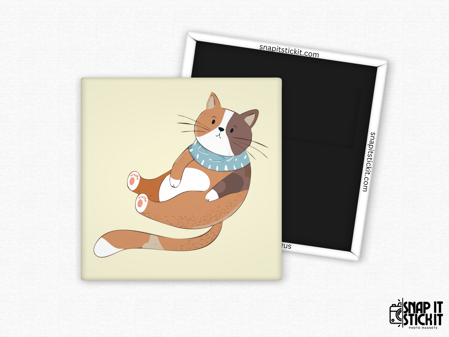 Cozy calico cat fridge magnet – 2x2” square magnet featuring a cartoon calico cat lounging with a blue winter scarf on a cream background. Strong magnetic back with Snap It Stick It branding. Cute and cozy gift for cat lovers, fall decor, or winter vibes.