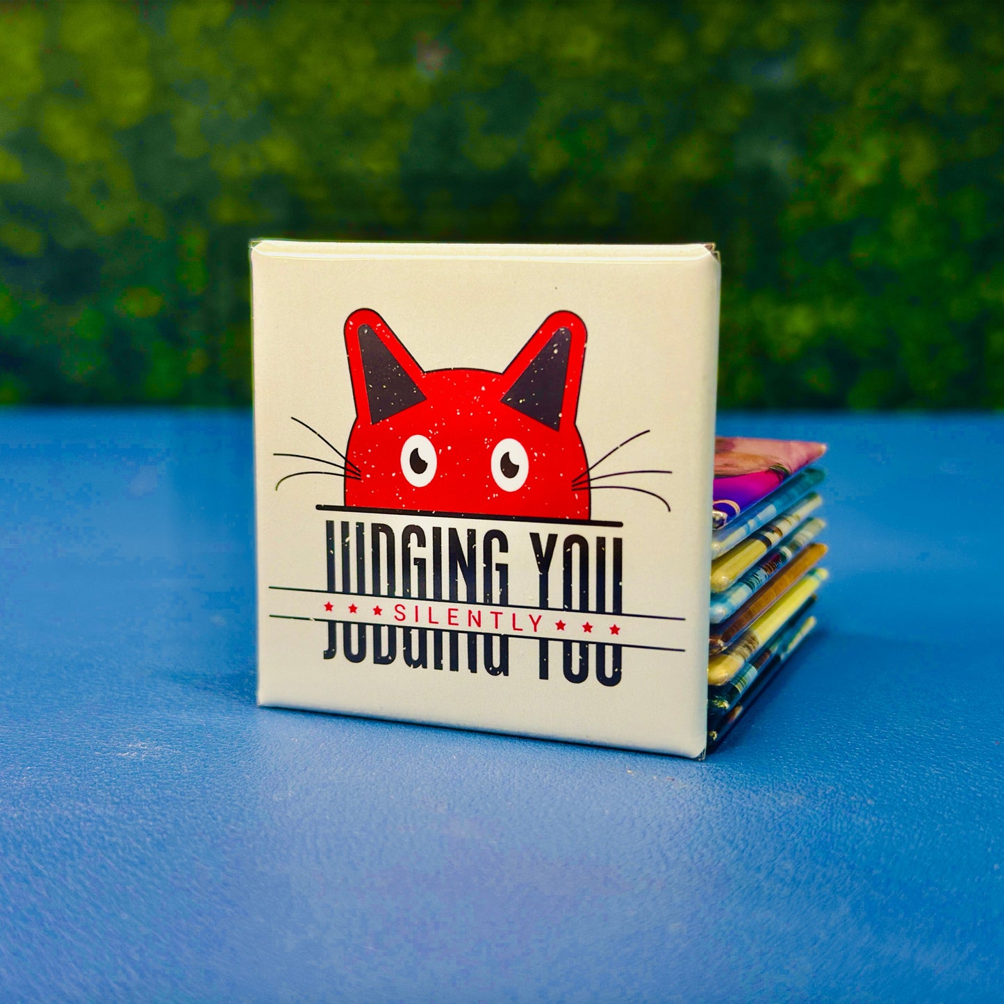 Square magnet featuring a bold red cartoon cat peeking above the sarcastic phrase “Judging You Silently” in distressed black and red lettering. Perfect for cat lovers with attitude, sassy pet parents, or anyone who appreciates dark humor. A hilarious cat-themed gift for birthdays, stocking stuffers, or fridge flair. Great for office desks, lockers, or snarky home decor.