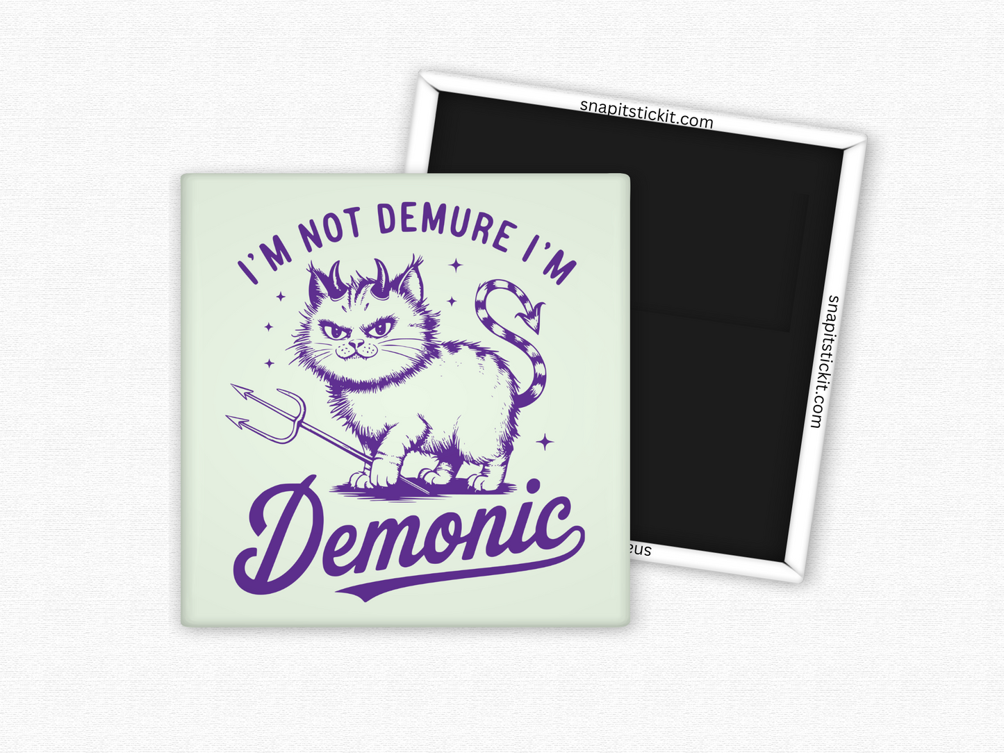 Square magnet with a vintage-style illustration of a mischievous cat holding a trident, featuring devil horns and a striped tail, with the phrase ‘I’m Not Demure I’m Demonic’ in bold purple text.