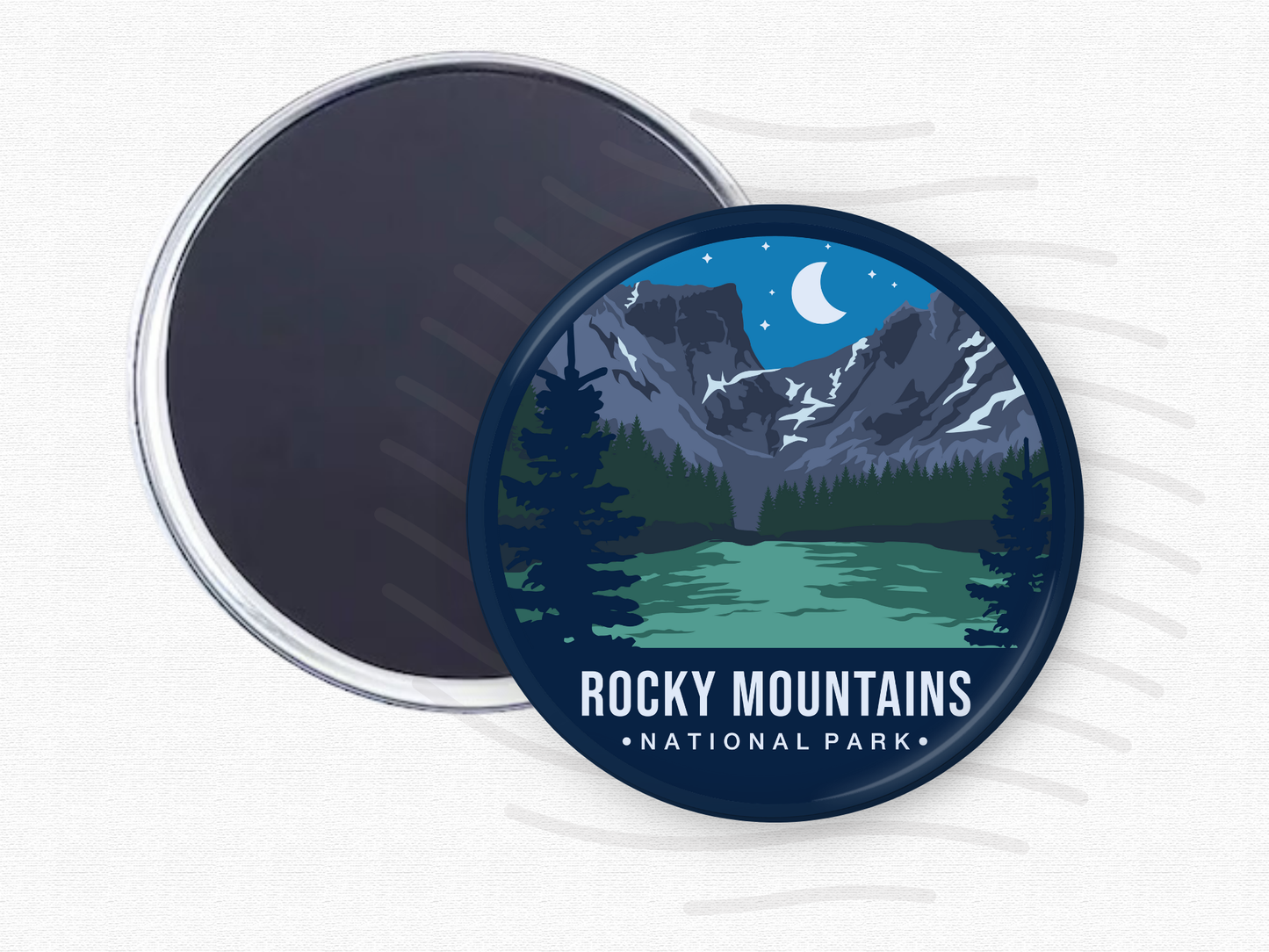 Round magnet of Rocky Mountains National Park featuring snow-capped peaks under a crescent moon, with a green alpine lake and dark pine trees in the foreground