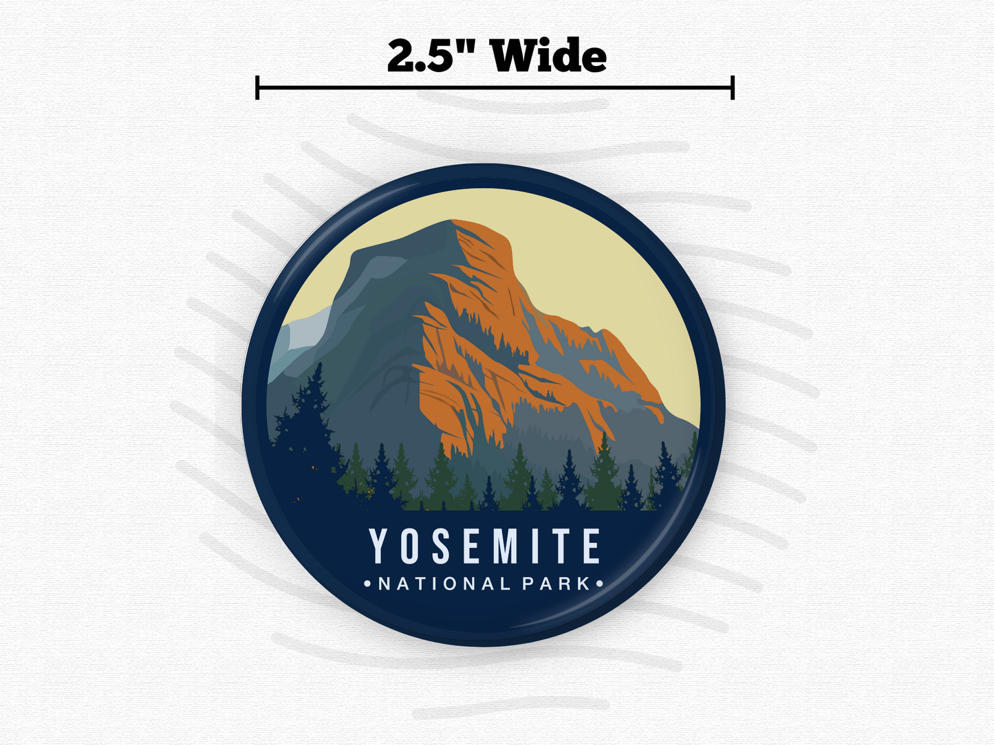 Round magnet of Yosemite National Park showcasing a majestic granite mountain with orange and blue hues, framed by dense evergreen trees under a soft beige sky.