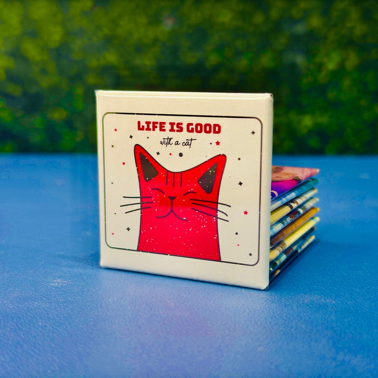 Square magnet with a red cartoon cat smiling under the phrase “Life Is Good With a Cat” in bold red and handwritten script. Surrounded by playful stars, this magnet brings charm and feline joy to fridges, lockers, or desks. A purr-fect gift for cat moms, cat dads, or anyone who knows that life really is better with a kitty around.