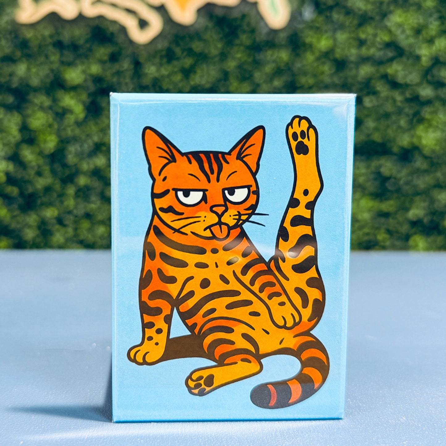 Card with a cartoon tiger design on a blue background, placed on a surface with a blurred green and orange abstract art in the background.