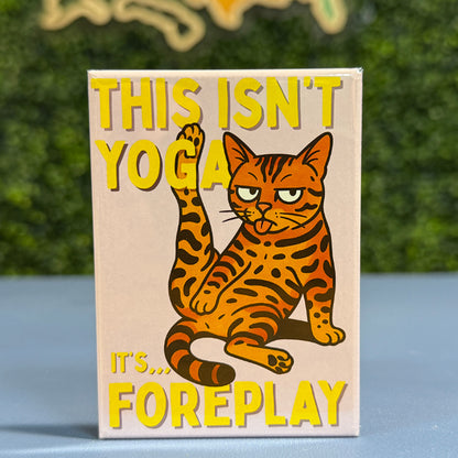 Magnet with a bengal cat illustration and humorous text on a wooden surface with a blurred green background