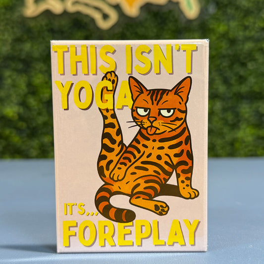 Magnet with a bengal cat illustration and humorous text on a wooden surface with a blurred green background