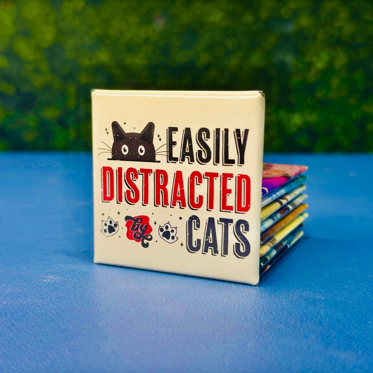 Funny cat magnet featuring a wide-eyed black cartoon cat, paw prints, and bold lettering that reads “Easily Distracted by Cats.” Retro color scheme and distressed design give it vintage charm. Perfect gift for cat moms, pet lovers, or anyone who proudly admits cats steal their focus. Great for fridges, lockers, cubicles, or as a fun addition to your feline-themed decor collection.