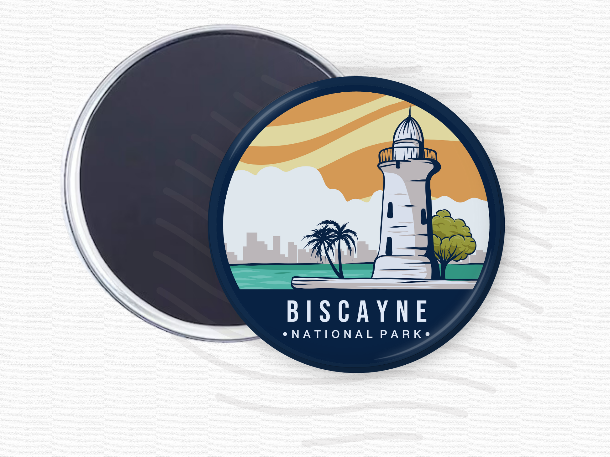 “Round magnet featuring Biscayne National Park with a coastal lighthouse, palm trees, and city skyline under a golden sunset sky.”