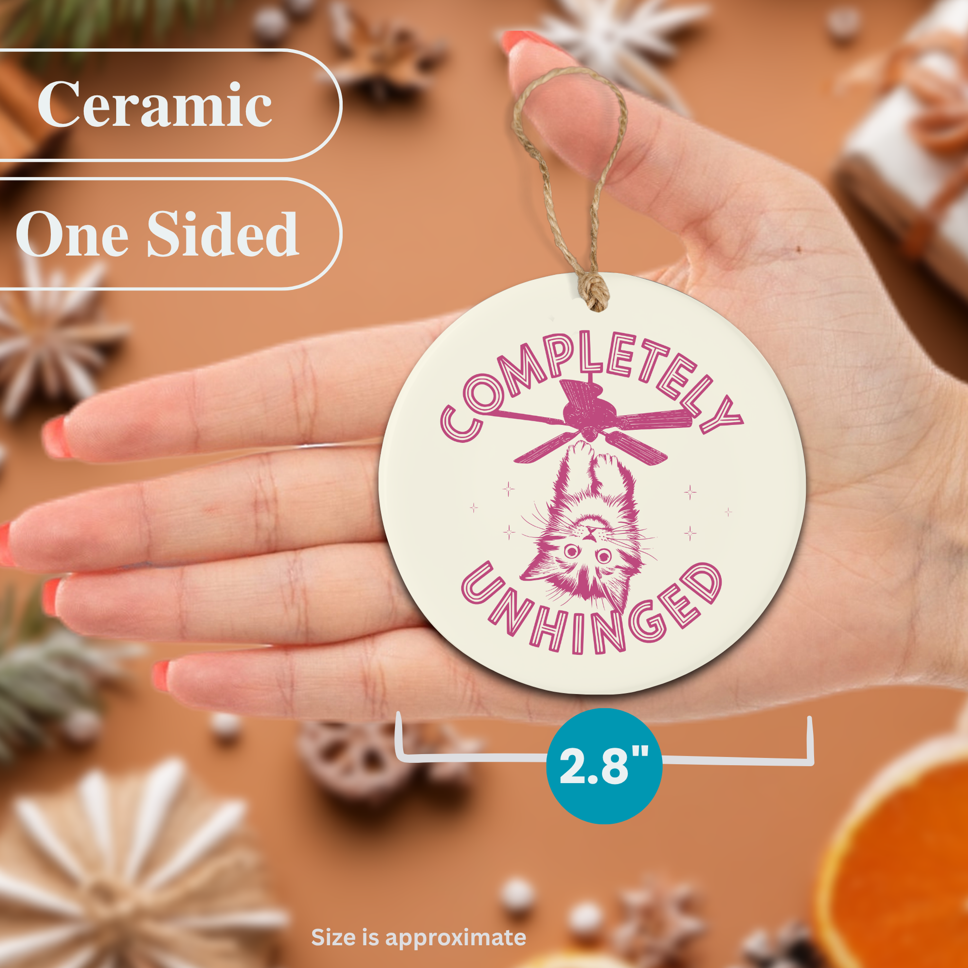Ceramic Christmas ornament with 'Completely Unhinged' design held in a hand, surrounded by decorative items.