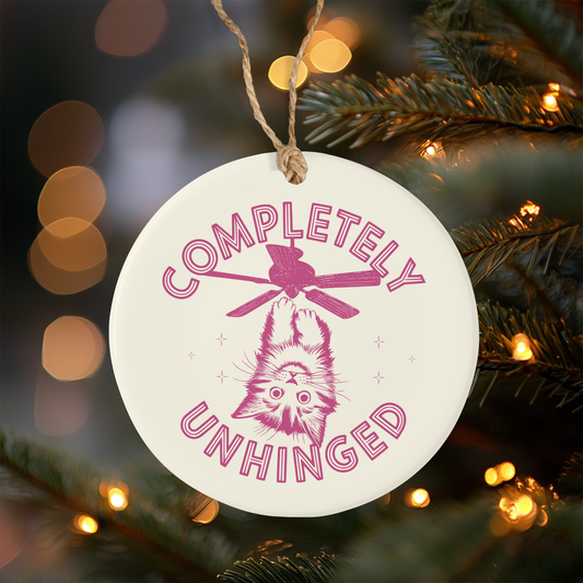 Ceramic Christmas Ornament with 'Completely Unhinged' text and cat illustration on a Christmas tree.