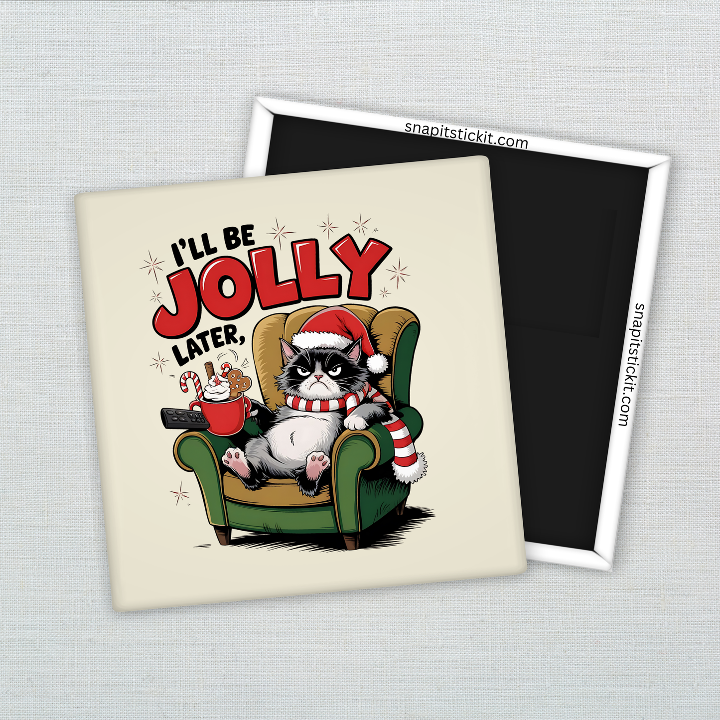 Grumpy black-and-white cat in a Santa hat and striped scarf, sitting in a green chair holding cocoa and cookies. Text: “I’ll Be Jolly Later.” 2x2 magnet.