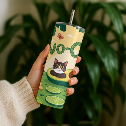 Person holding a tumbler with avocado and cat design against a blurred green plant background