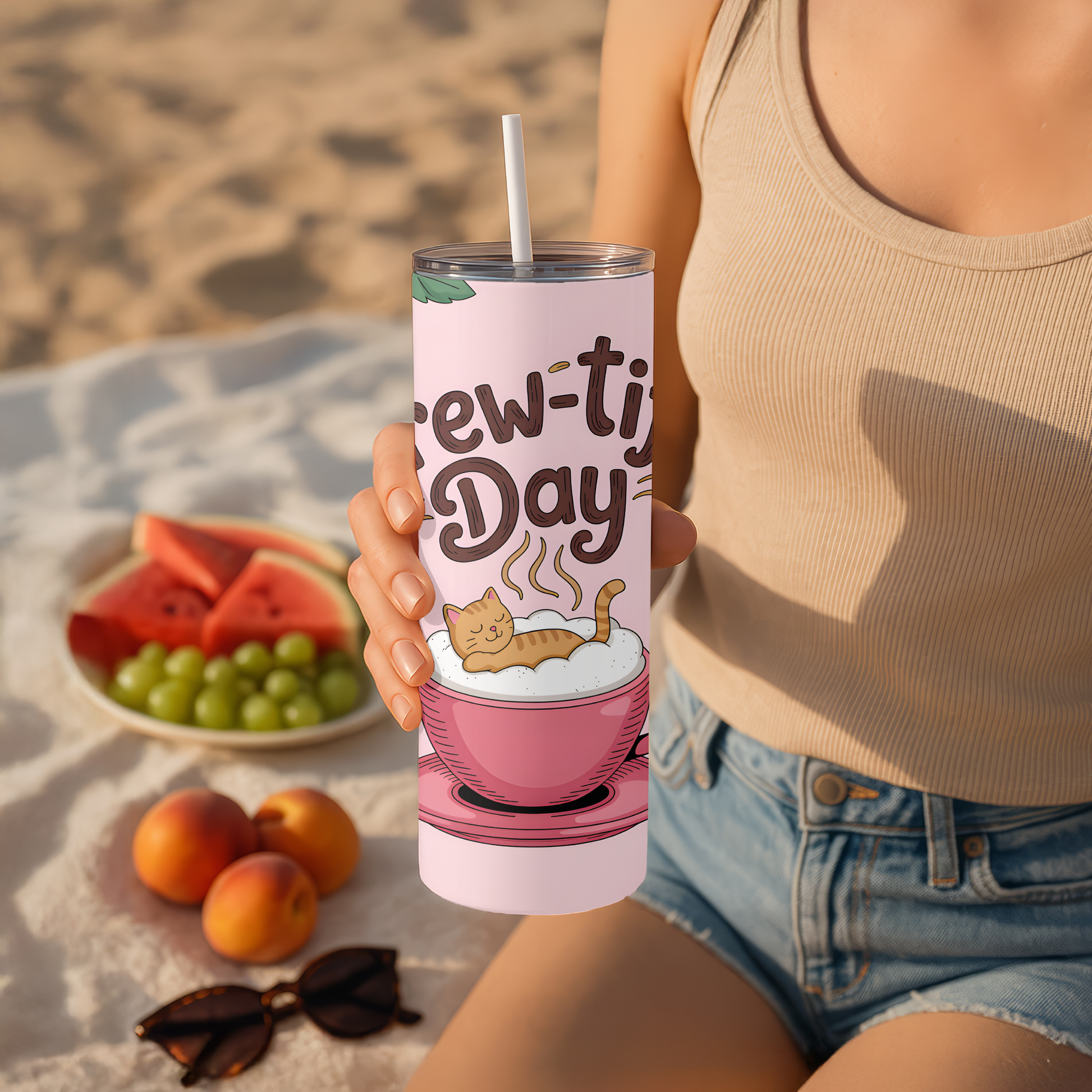 Person holding a  tumbler with a beach setting and fruit plate in the background