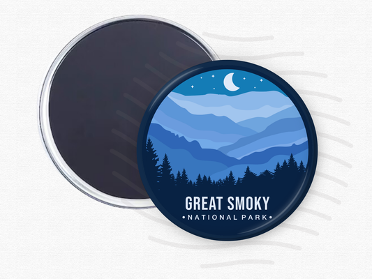 Round magnet of Great Smoky Mountains National Park featuring layered blue mountain ridges under a crescent moon and starry night sky with a silhouette of pine trees in the foreground.