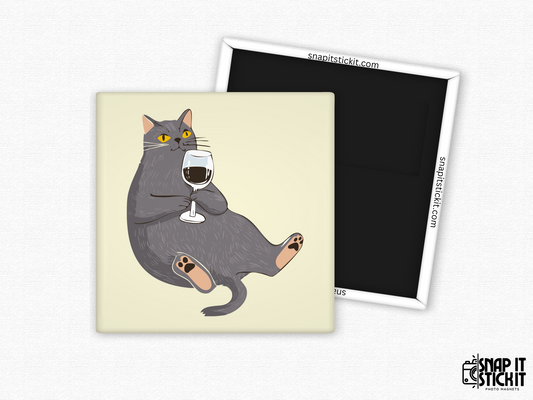 Funny wine cat magnet – square 2x2” fridge magnet with a dark gray cartoon cat lounging with a glass of red wine. Strong magnetic back shown with Snap It Stick It branding. Great gift for cat lovers and wine enthusiasts.