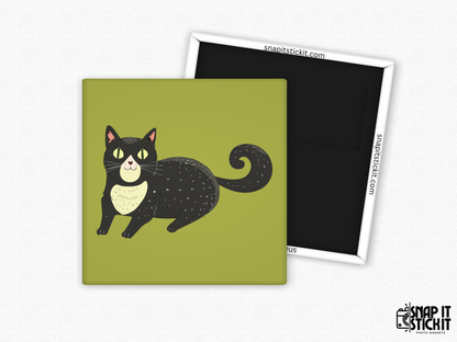 Cute black cat fridge magnet – 2x2” square magnet featuring a smiling cartoon black cat with yellow eyes, curly tail, and cream chest patch on a green background. Strong magnetic back with Snap It Stick It branding. Fun gift for cat lovers, Halloween fans, or quirky decor.