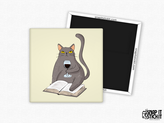 Gray cat with wine and book fridge magnet – 2x2” square magnet featuring a cartoon gray cat sitting on an open book and holding a glass of red wine. Cream background with strong magnetic back and Snap It Stick It branding. Perfect gift for cat lovers, bookworms, and wine moms.