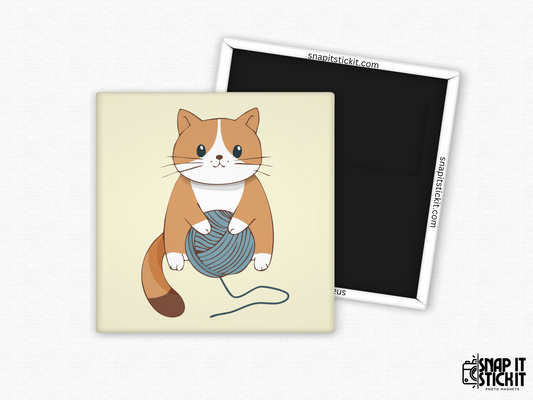 Orange cat playing with yarn fridge magnet – 2x2” square magnet featuring a cartoon orange and white cat holding a ball of blue yarn on a light beige background. Strong magnetic back with Snap It Stick It branding. Ideal gift for cat lovers, crafters, or cozy home decor fans.
