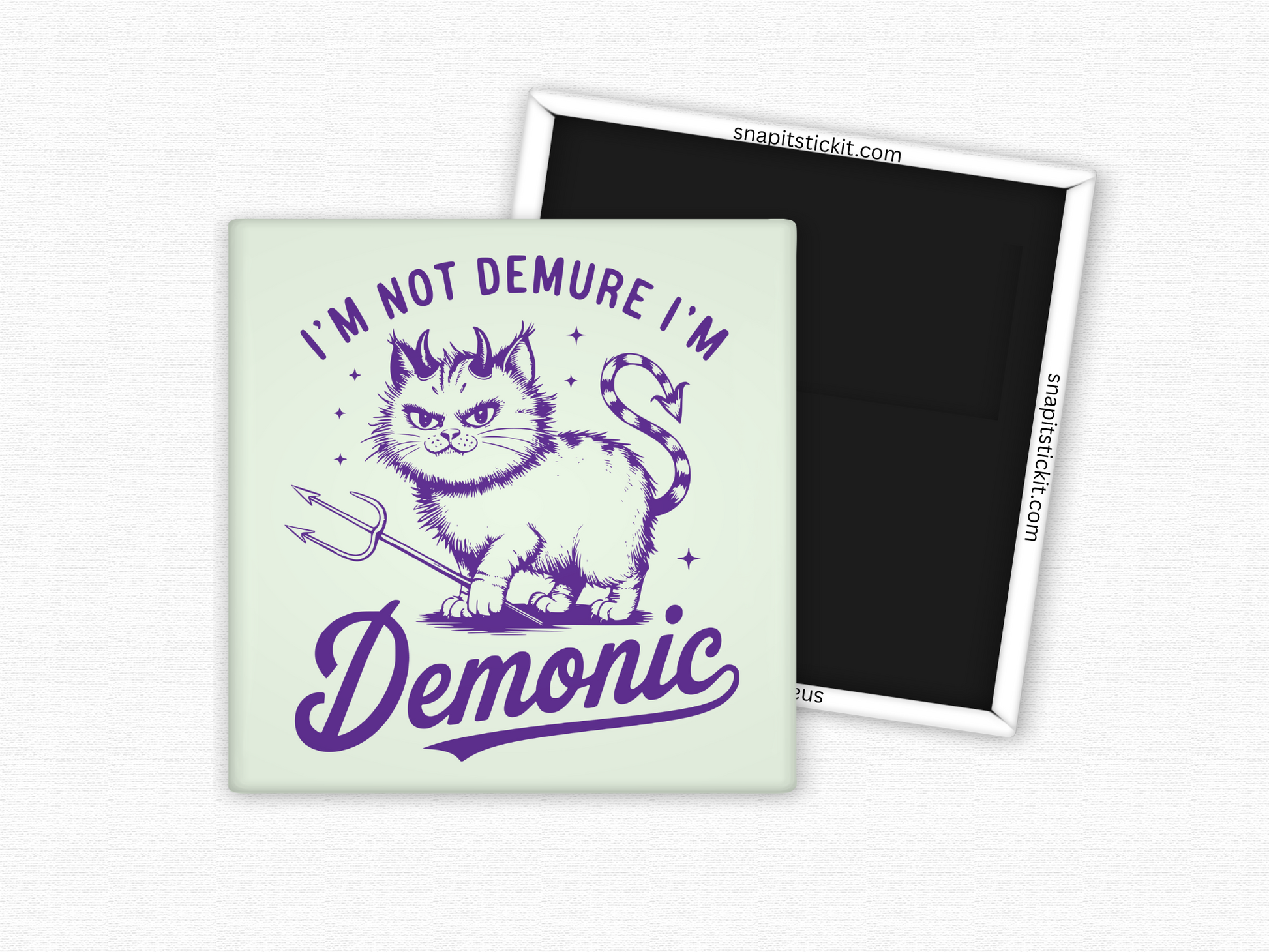 Square magnet with a vintage-style illustration of a mischievous cat holding a trident, featuring devil horns and a striped tail, with the phrase ‘I’m Not Demure I’m Demonic’ in bold purple text.