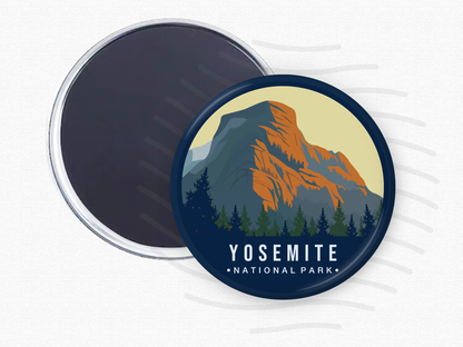 Round magnet of Yosemite National Park showcasing a majestic granite mountain with orange and blue hues, framed by dense evergreen trees under a soft beige sky.